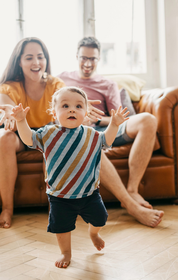 happy mom and dad watching their baby walk