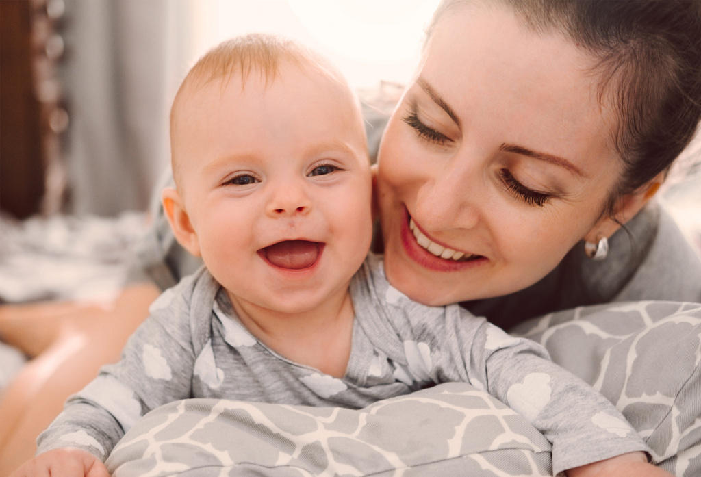 Usmiechnięta mama z dzieckiem na łóżku