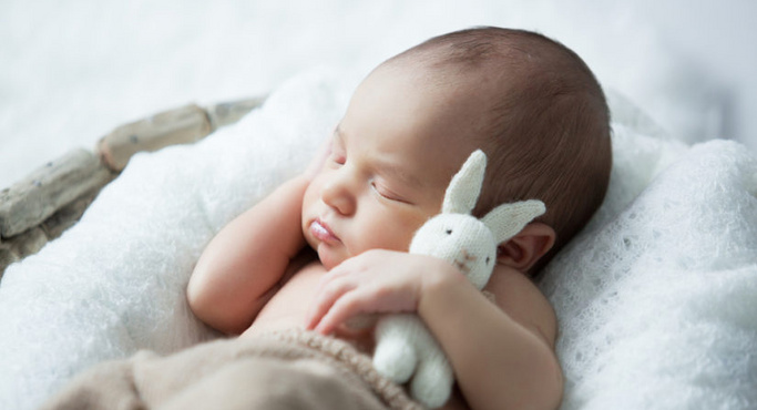 Śpiący noworodek przytulający zabawkę