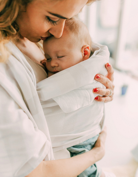 Mama przytulająca się do śpiącego noworodka