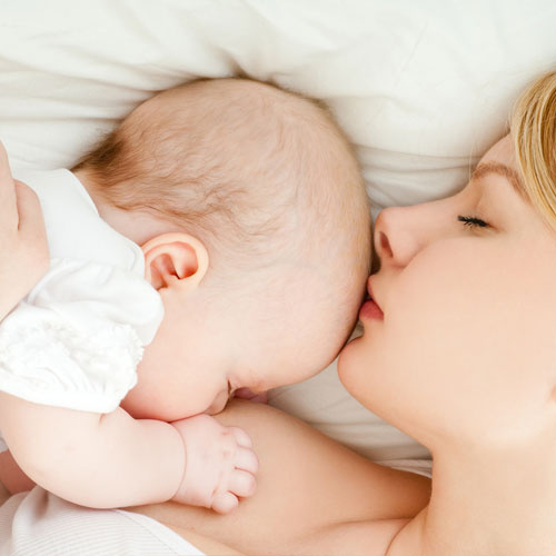Mama przytulająca noworodka w łóżku